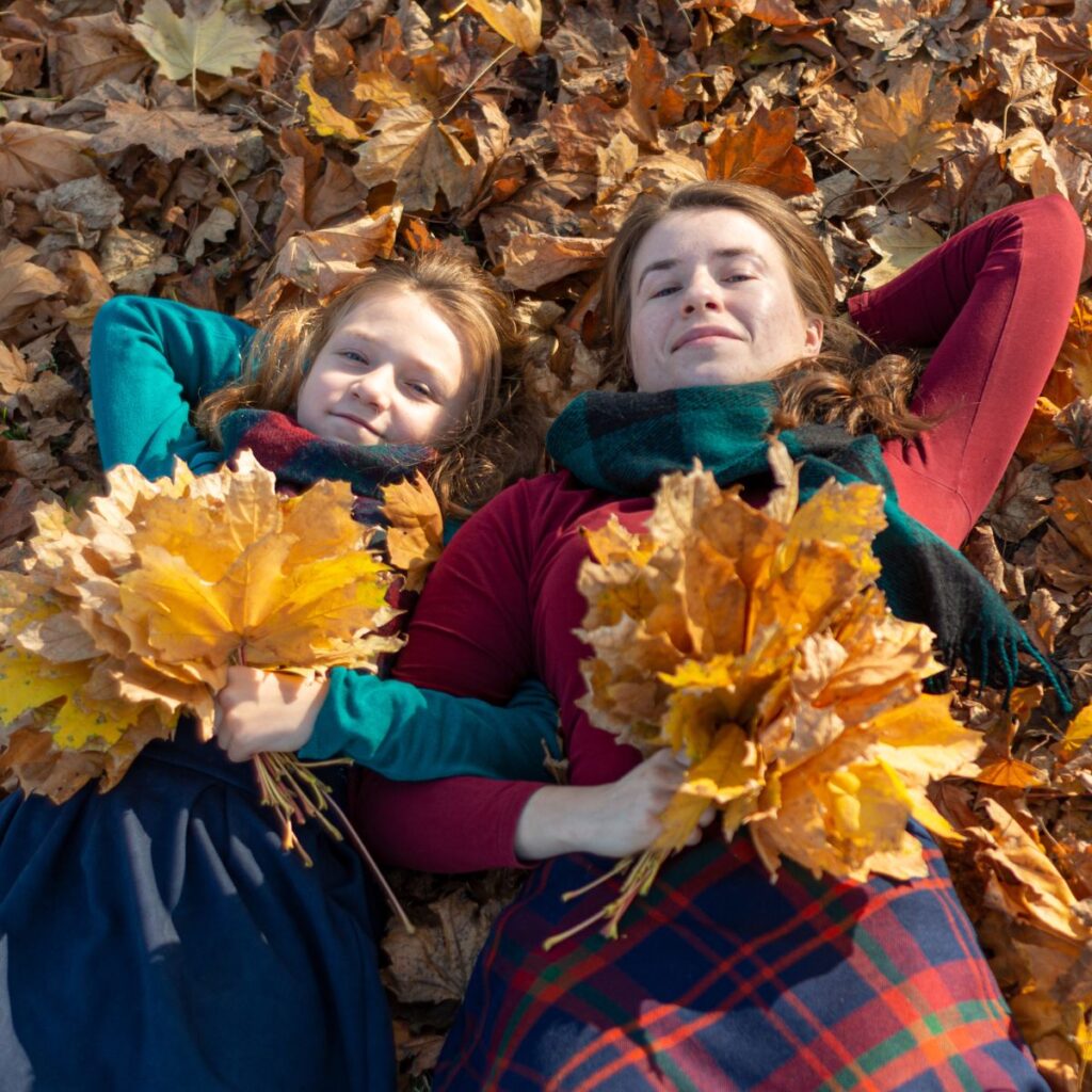 mother and daughter holding handfuls of fall leaves